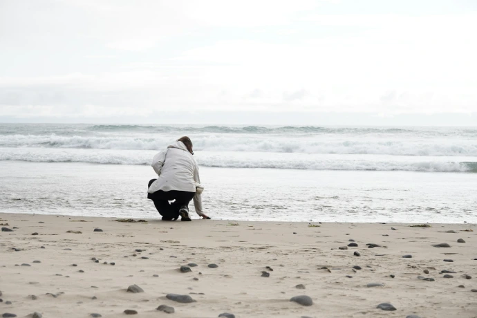 Person sits by the ocean.